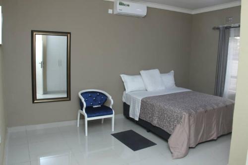 1 dormitorio con cama, espejo y silla en GOLDLAND APARTMENTS en Kitwe