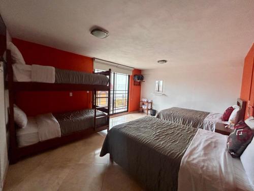 - 2 lits dans une chambre aux murs rouges dans l'établissement Hotel MH, à Chignahuapan