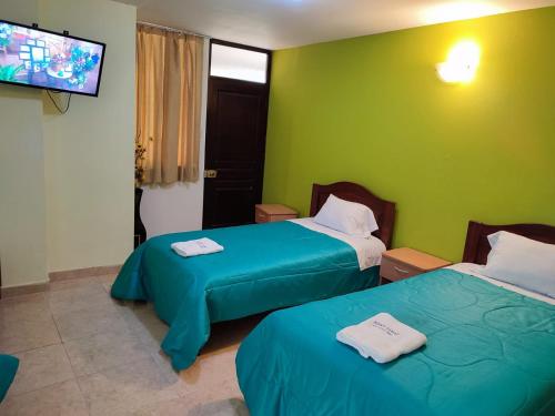 two beds in a room with green walls at Hotel Misky Samay in Ayacucho