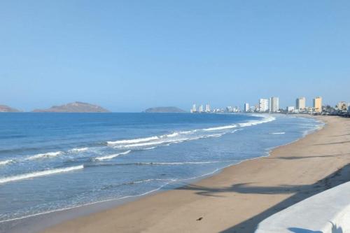 a beach with the ocean and buildings in the background at Malecón Casa Grande Económica Gran Ubicación in Mazatlán