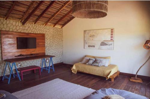 a living room with a couch and a table with a tv at Magaral Casa de Praia in Pôrto de Pedras