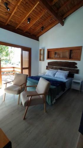 a bedroom with a bed and two chairs and a table at Cabana Linha Brasil in Nova Petrópolis