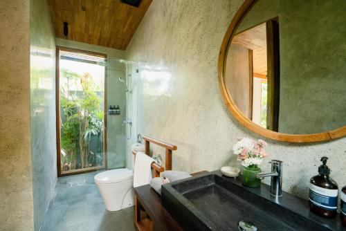 a bathroom with a sink and a toilet and a mirror at The Surf Shack - Stylish New 1 BR Studio w/ plunge pool in Uluwatu