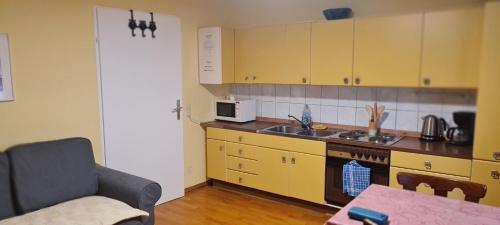 a kitchen with yellow cabinets and a sink and a couch at Ulli 1 in Zell am See