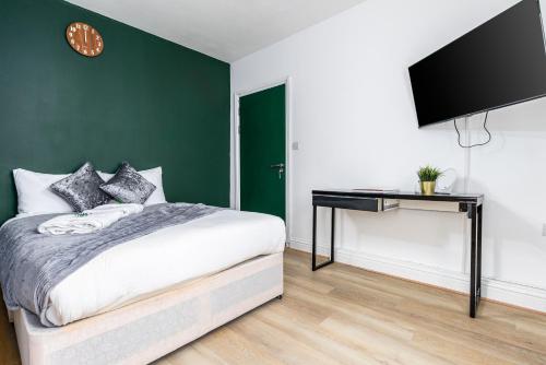 1 dormitorio con 1 cama y escritorio con TV en City Gate Guest House, en Londres