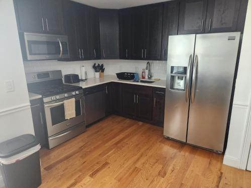 a kitchen with black cabinets and a stainless steel refrigerator at Spacious 1BR Apt Mins to NYC in Union City