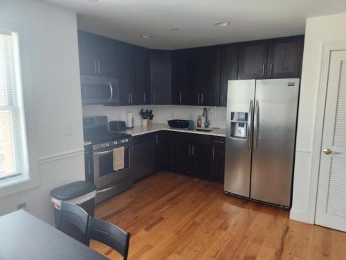 a kitchen with black cabinets and a stainless steel refrigerator at Spacious 1BR Apt Mins to NYC in Union City