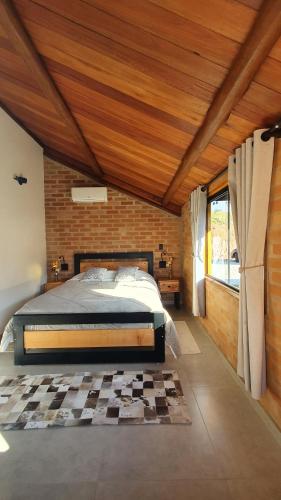 a bedroom with a bed and a brick wall at Pousada Ho'oponopono Chalets & Wine in Sapucaí-Mirim