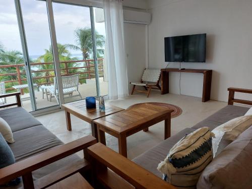 Noah Beach Hotel & Suites في ماهاهوال: غرفة معيشة مع أريكة وتلفزيون