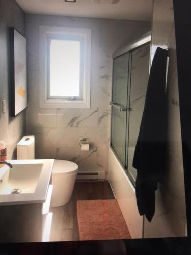 a bathroom with a sink and a toilet and a window at Le 10620 beau, grand et charmant 5 et demi in Quebec City