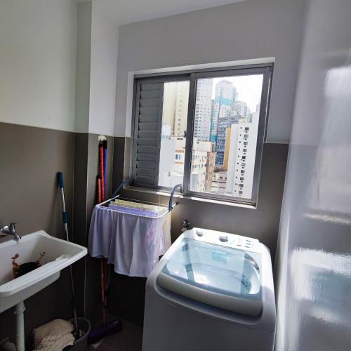 a bathroom with a toilet and a sink and a window at Apartamento Pertinho da Praia, faça tudo a pé! in Balneário Camboriú