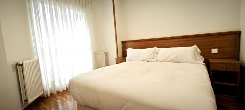 una camera da letto con un grande letto bianco e una finestra di Vistas Río Tormes Huerta Otea a Salamanca