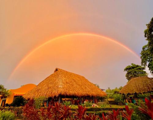 een regenboog in de lucht boven een hut bij Alma del Pacifico Hotel & Spa in Esterillos Este