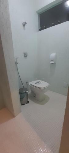 a white bathroom with a toilet and a window at Casa 6 quartos piscina e sauna in Rio de Janeiro
