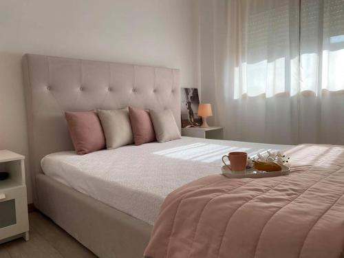 ein weißes Bett mit rosa Kissen und einem Tablett darauf in der Unterkunft DayDream Apartament in Viana do Castelo