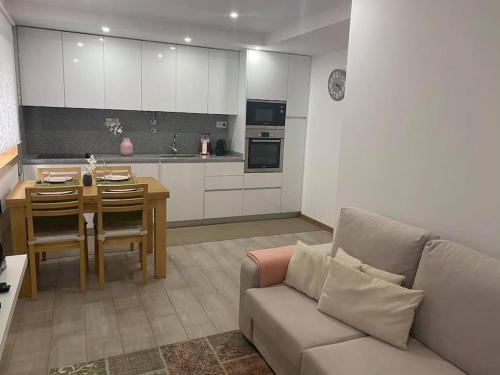ein Wohnzimmer mit einem Sofa und einem Tisch sowie eine Küche in der Unterkunft DayDream Apartament in Viana do Castelo