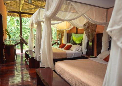 a bedroom with two beds and a canopy bed at Refugio Amazonas Lodge in Tambopata