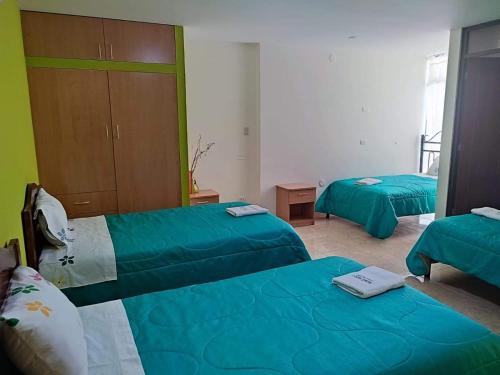 three beds in a room with green sheets at Hotel Misky Samay in Ayacucho