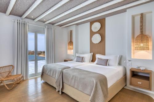 a bedroom with a large bed and a large window at Santa Marina, A Luxury Collection Resort, Mykonos in Ornos