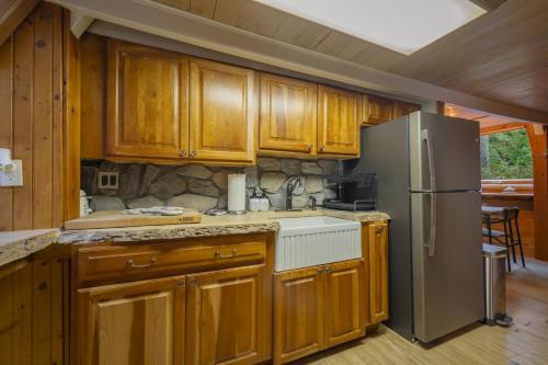 a kitchen with wooden cabinets and a stainless steel refrigerator at Enchanting River- Water Front A-Frame Cabin in Yulan