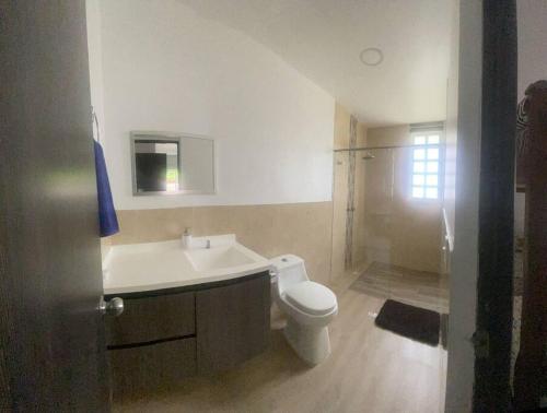 uma casa de banho com um WC branco e um lavatório. em Finca y Piscina de Ensueño em El Cerrito