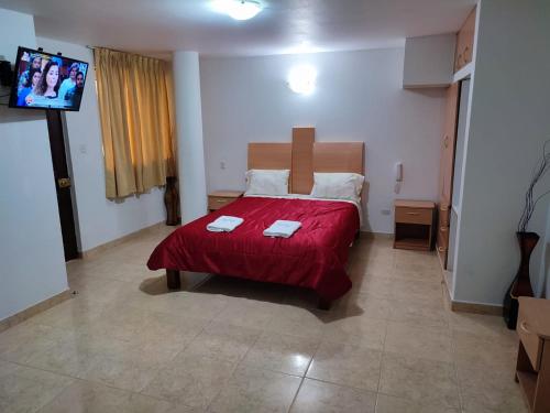 a bedroom with a bed with a red blanket at Hotel Misky Samay in Ayacucho