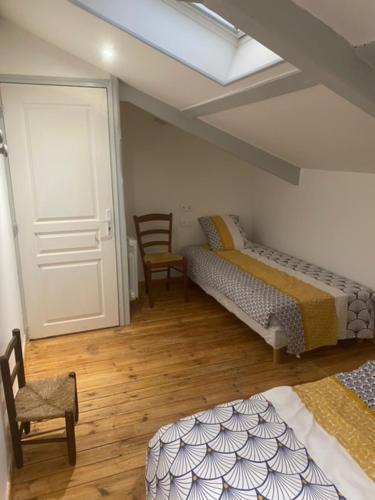 Cette chambre comprend deux lits, une porte et une chaise. dans l'établissement Jade, à Dompierre-sur-Charente