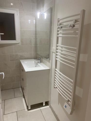 La salle de bains blanche est pourvue d'un lavabo et d'un miroir. dans l'établissement Jade, à Dompierre-sur-Charente