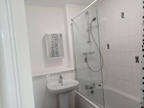 La salle de bains blanche est pourvue d'un lavabo et d'une douche. dans l'établissement LovelyHome 4 family& Contractors, à Killingbeck