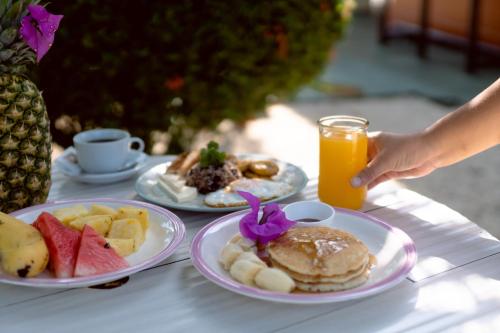 Hotel Villabosque Eco Boutique في مانويل أنطونيو: طاولة مع أطباق من طعام الإفطار وكوب من عصير البرتقال