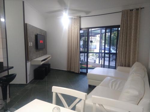 ein Wohnzimmer mit einem weißen Sofa und einem Tisch in der Unterkunft Condomínio Buritis Centro de Bertioga a 100Mts da praia in Bertioga