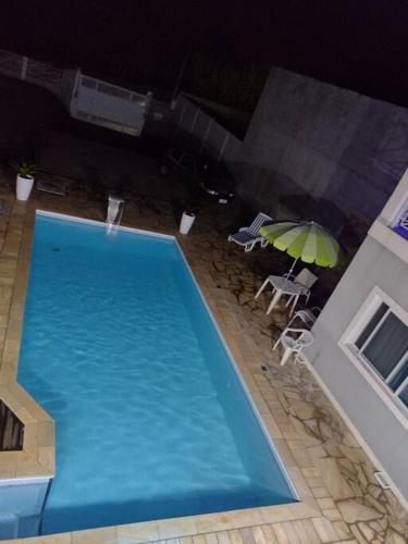 a large blue swimming pool with an umbrella and chairs at Linda casa em condomínio fechado para temporada. in Itatiba