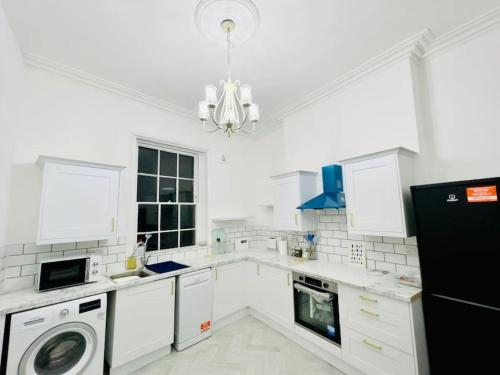 a kitchen with white appliances and a black refrigerator at Flat 4 Marine Parade House, 1 East Cliff- Next to Dover Port, White Cliffs, Beach, Castle in Dover