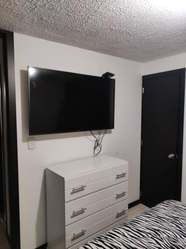 een slaapkamer met een flatscreen-tv aan de muur bij APARTAMENTO CERCA A LA SENDA DEL CARNAVAL in Pasto