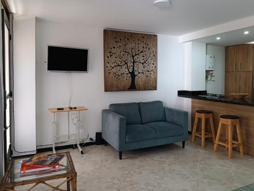 sala de estar con sofá azul y TV en Acogedor apartaestudio ubicado en Laureles, en Medellín