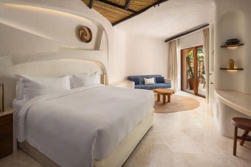 a bedroom with a white bed and a living room at Hotel Cala di Volpe, a Luxury Collection Hotel, Costa Smeralda in Porto Cervo