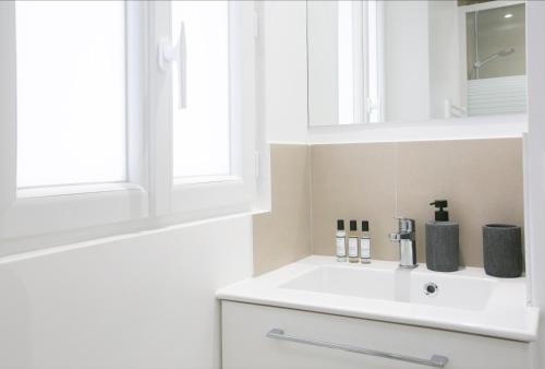 une salle de bain blanche avec un lavabo et un miroir dans l'établissement Charming 1 Bedroom Marais Hideaway - FB17A, à Paris