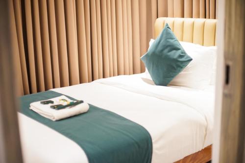 a bed with a green pillow and a tray on it at Solano Residences in Lipa