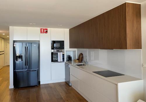 een keuken met een zwarte koelkast en witte kasten bij Tranquillity On The Promenade in Batemans Bay