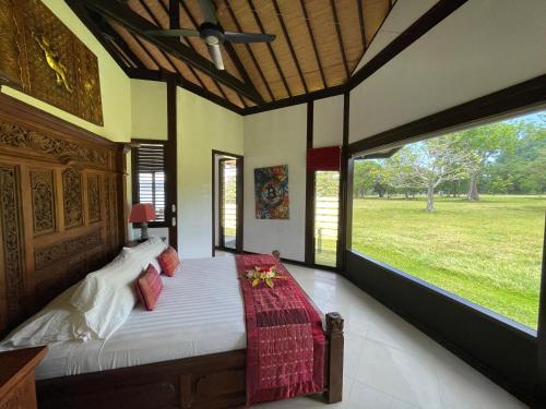 een slaapkamer met een groot bed en een groot raam bij Private Island Stay in Vitouara