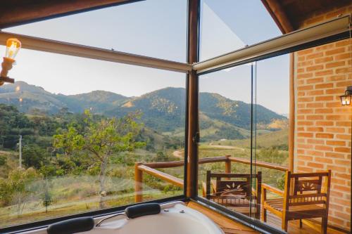 a room with a window with a view of mountains at Pousada Ho'oponopono Chalets & Wine in Sapucaí-Mirim