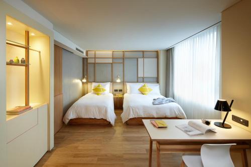 a hotel room with two beds and a desk at L7 MYEONGDONG by LOTTE in Seoul
