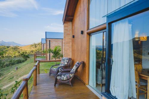 a balcony with two chairs on a wooden deck at Pousada Ho'oponopono Chalets & Wine in Sapucaí-Mirim