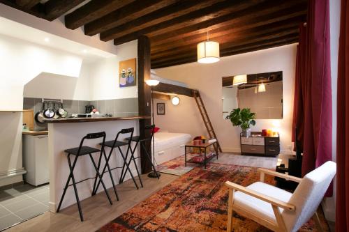 Il comprend une cuisine et un salon avec un comptoir et des chaises. dans l'établissement Authentic apartment in center of Parisian Marais, à Paris