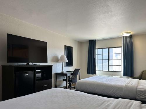 a hotel room with two beds and a flat screen tv at Clarion Pointe Winslow I-40 in Winslow
