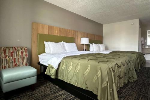 a hotel room with a large bed and a chair at Quality Inn Calhoun North I-75 in Calhoun