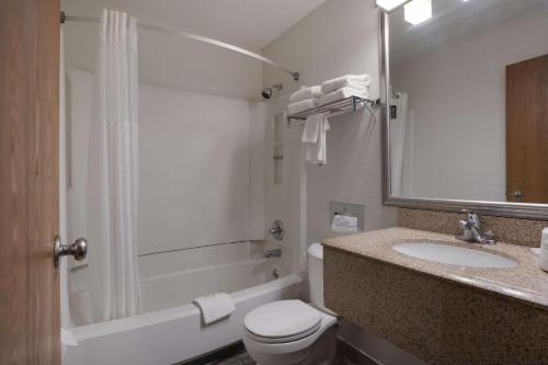 a bathroom with a toilet and a sink and a tub at Quality Inn Hall of Fame in Canton