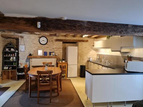 une cuisine et une salle à manger avec une table et une horloge dans l'établissement Maison charmante rénovée avec jardin près de Fontainebleau et de la forêt d'Orléans - FR-1-590-114, à Beaune-la-Rolande