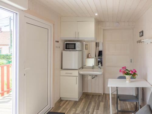 une petite cuisine avec un évier et un micro-ondes dans l'établissement Chambre élégante, calme et adaptée PMR avec Wi-Fi, climatisation, parking et table d'hôtes - FR-1-590-266, à Noyers