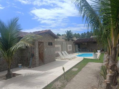 ein Haus mit einem Pool und Palmen in der Unterkunft Casa em condomínio na praia de Paripueira AL in Paripueira